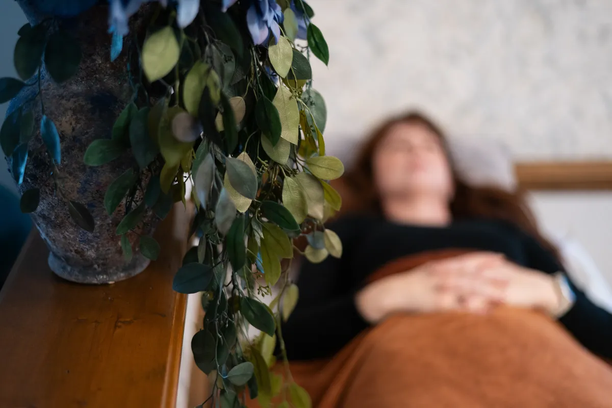 A woman resting comfortably beside a plant during a PEMF session