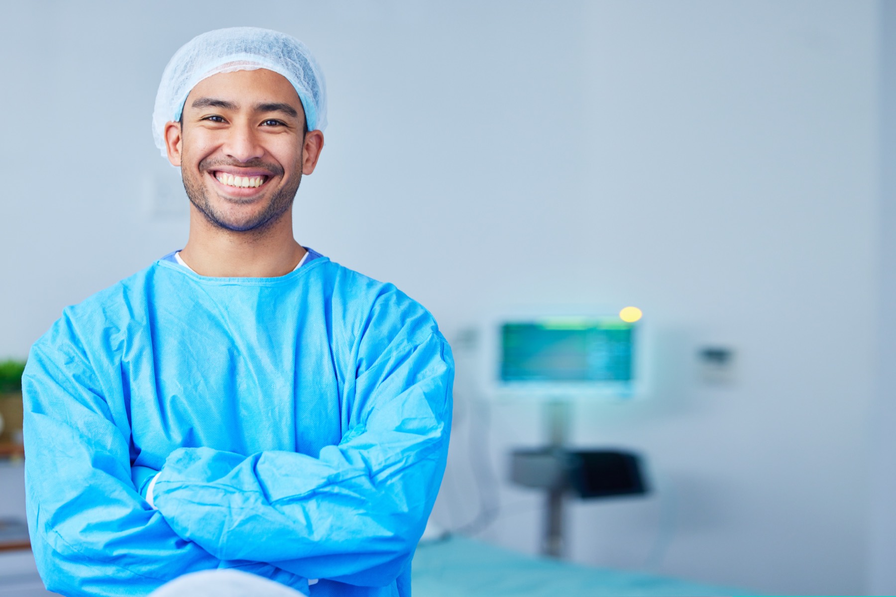 A smiling surgeon in surgical attire in an operating room